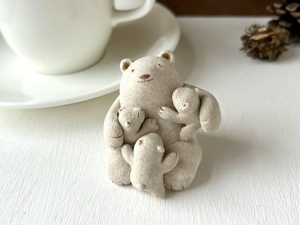 甘えん坊が愛しくて（三人抱っこ）。陶土粘土製のクマさんの小さな置物。子グマさんトリオはクマさんに甘えています。